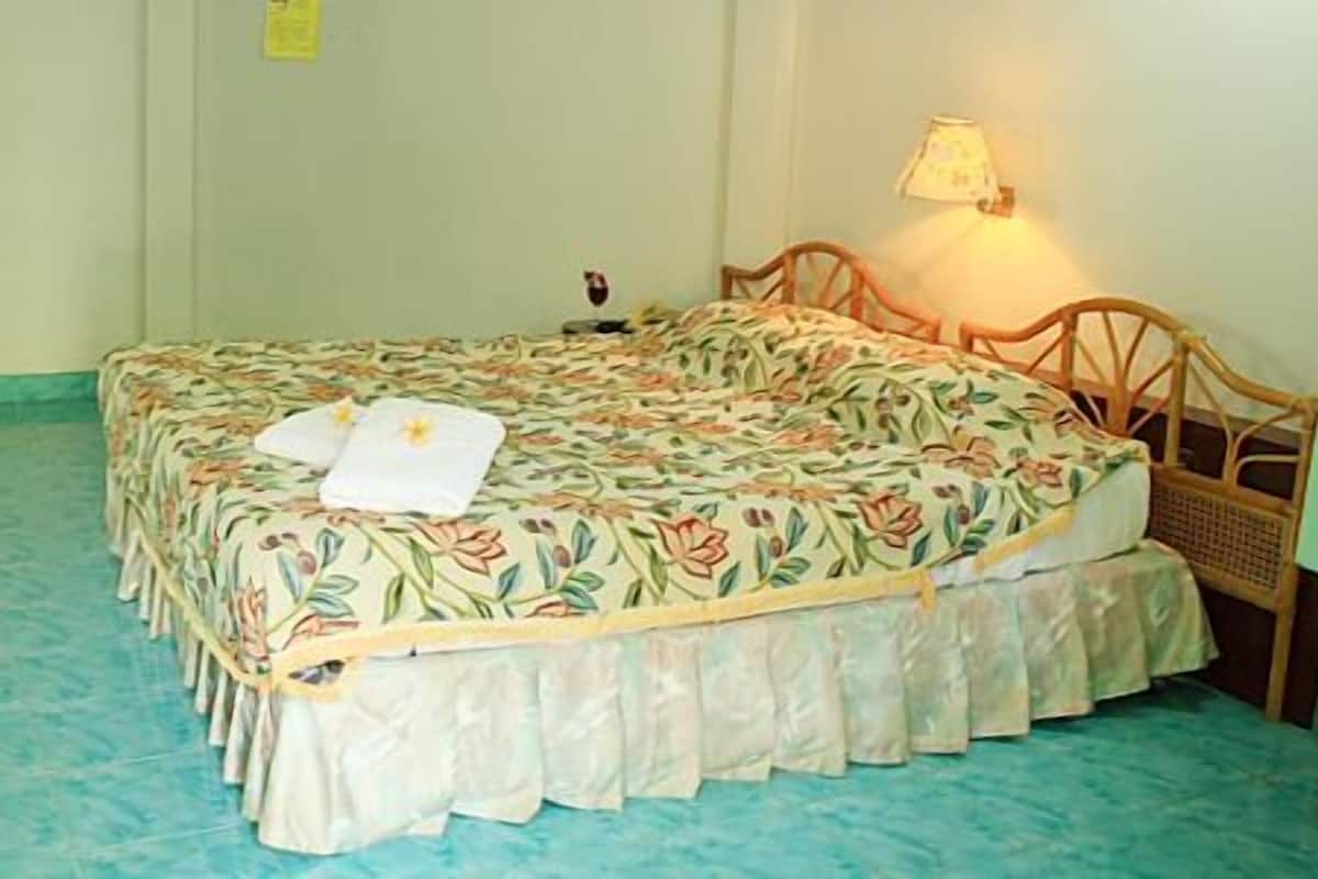 A single bed with floral bedding, a wooden headboard, and a bedside lamp.