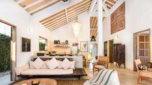 A spacious living area with a high ceiling, a modern kitchen, and a cozy seating area with a sofa and chairs. - Villa 007 (Seminyak)