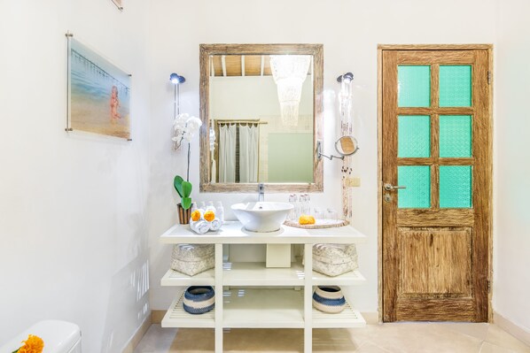 A bathroom with a white sink, mirror, and wooden door. - Villa 007 (Seminyak)