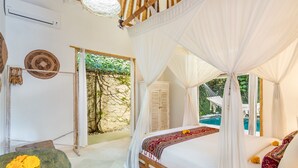 A bedroom with a bed under a canopy, a view of a swimming pool, and a table with flowers. - Villa 007 (Seminyak)