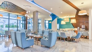 A modern restaurant with blue seating, large windows, and a contemporary interior design. - Hotel Bracera (Budva)