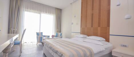 Habitación de hotel con cama, mesita de noche, silla y vistas al exterior.
