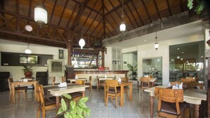 Un restaurant spacieux avec des tables et des chaises en bois, un coin bar et un écran de télévision.