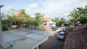Une terrasse offrant une vue dégagée sur une rue en contrebas, avec des voitures garées et des immeubles.