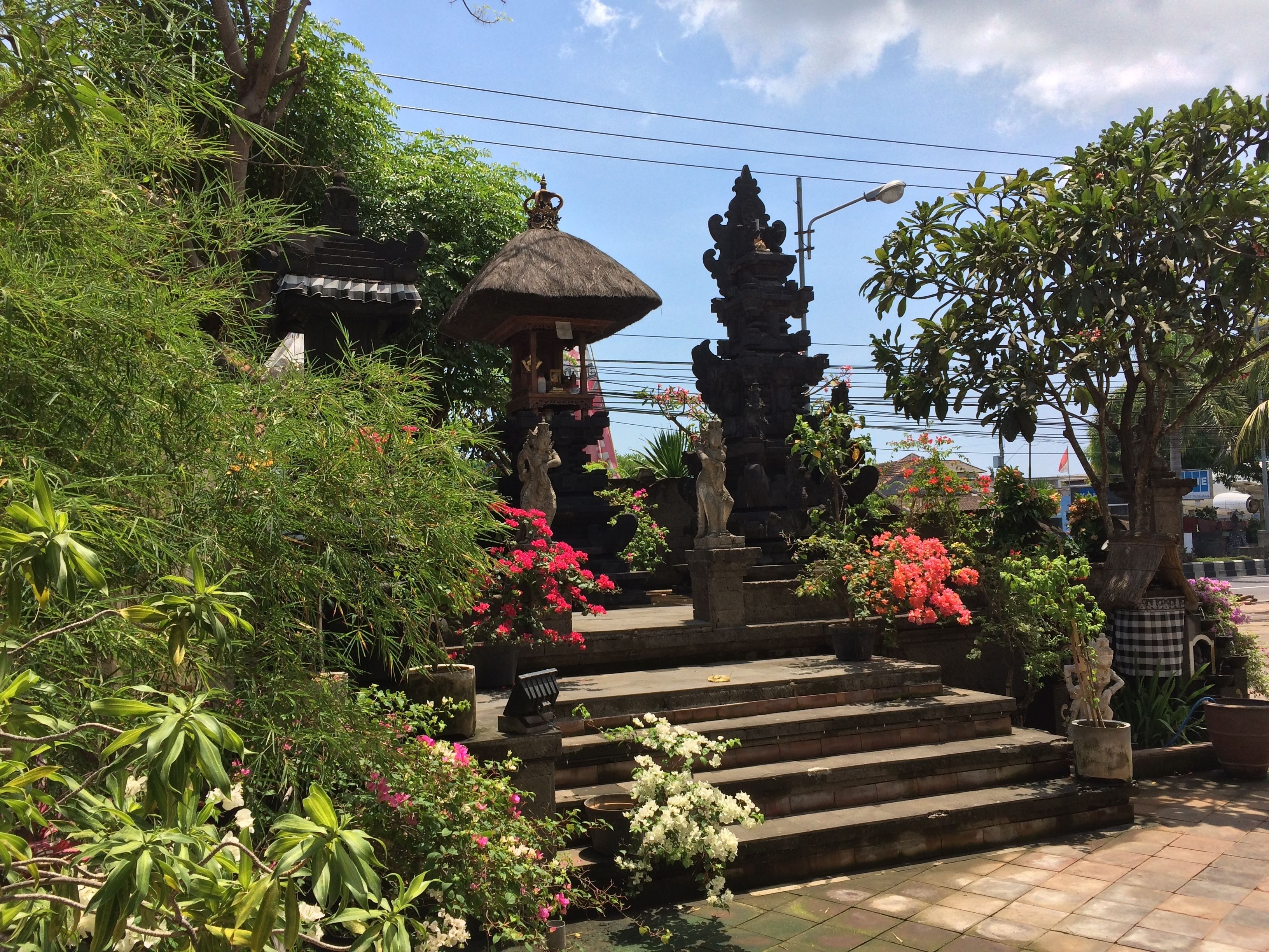 A garden with steps leading to a gazebo, surrounded by various plants and flowers.