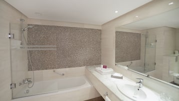A modern bathroom with a glass-enclosed shower, a large mirror, and a marble countertop.