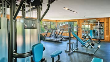 A gym with exercise equipment, benches, and a large mirror.