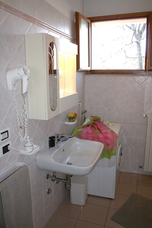 A bathroom with a sink, mirror, and window.