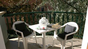 A balcony with a white table and two white chairs, a white lantern, and a book. - Residenza Novalba (Riccione)