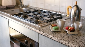 A kitchen with a gas stove, sink, and a coffee maker. - Residenza Novalba (Riccione)