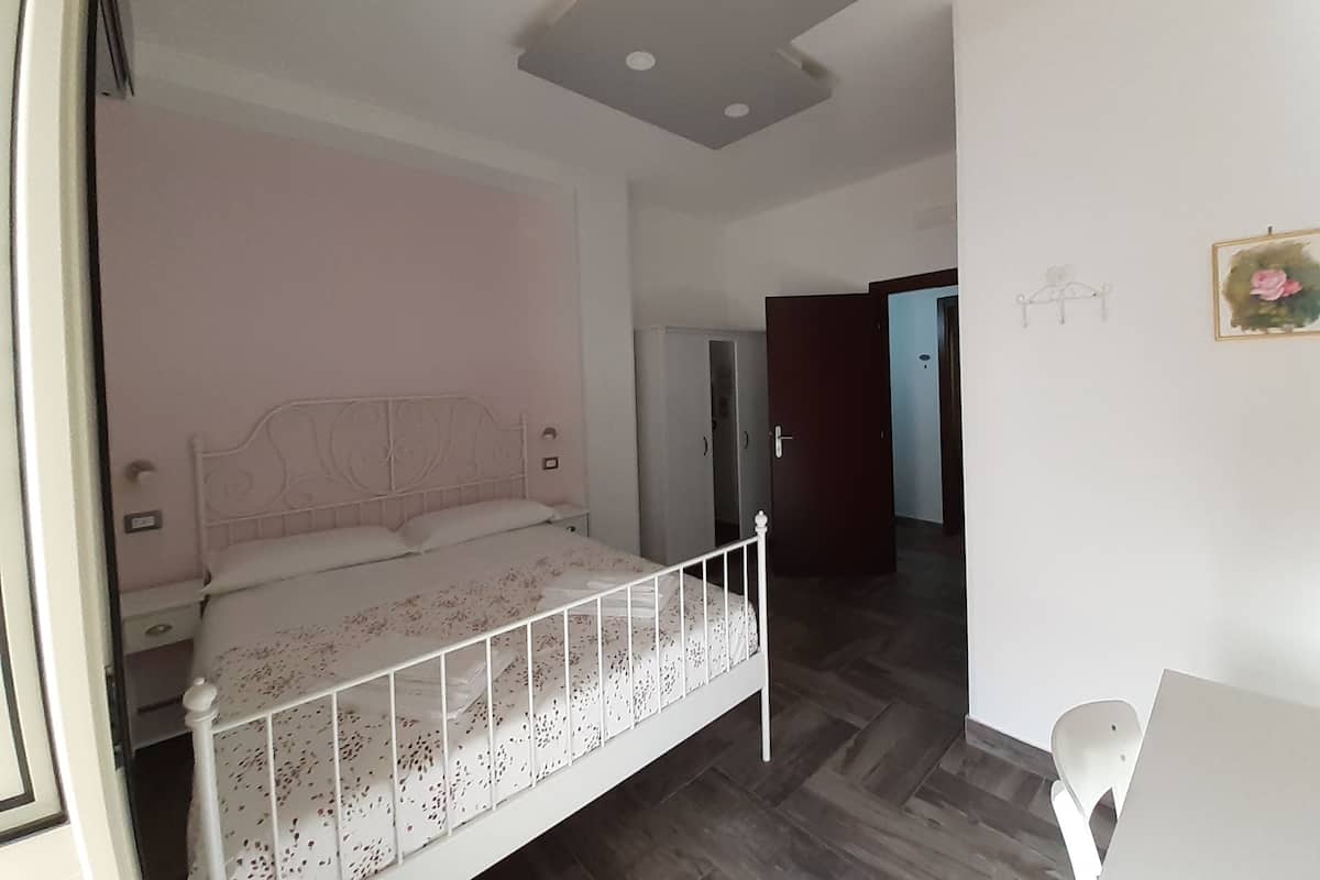 A bedroom with a bed, a wardrobe, and a door leading to another room.