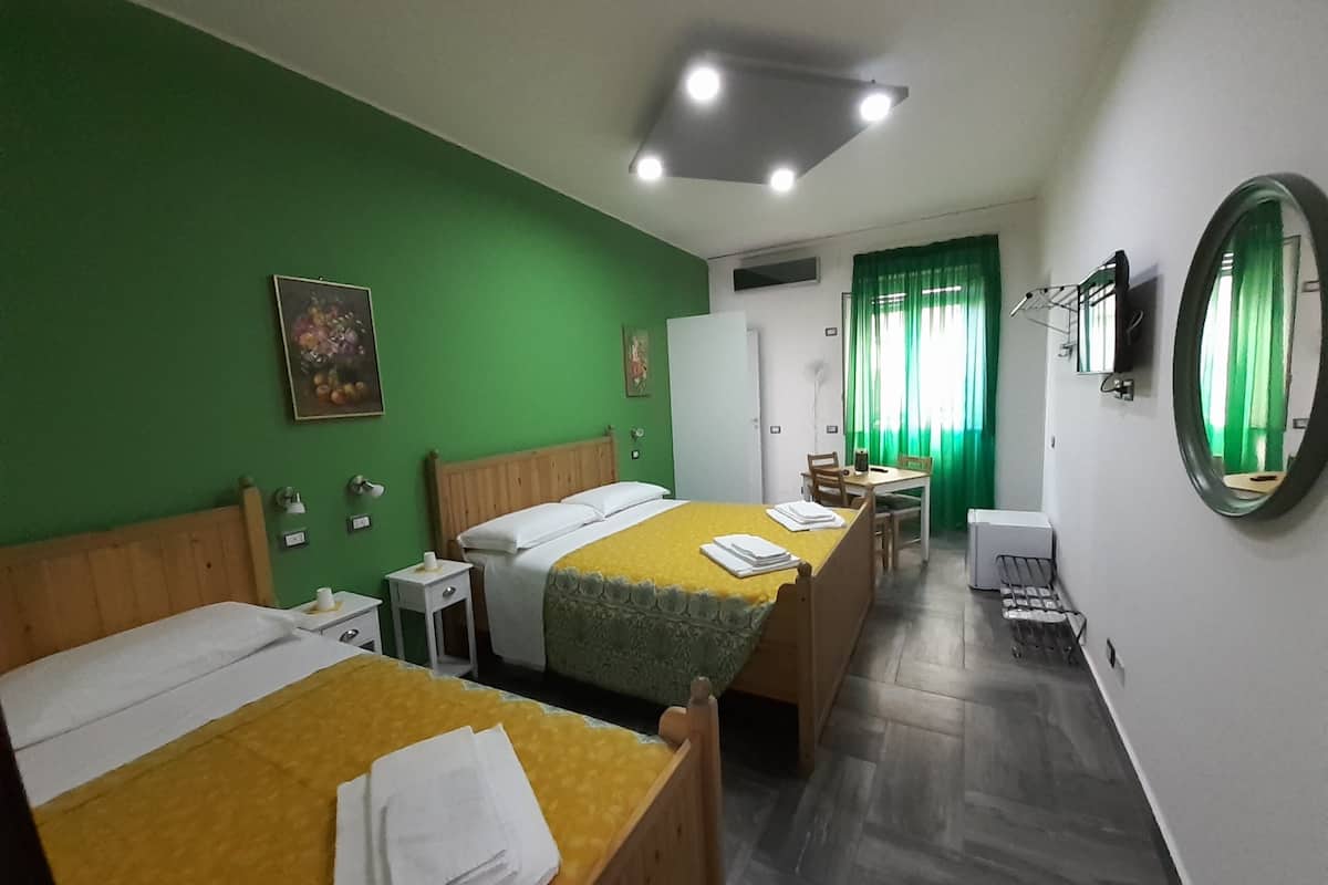 A hotel room with two beds, a desk, a chair, a mirror, and a window with curtains.
