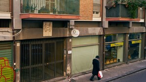A building with a closed shutter, a sign indicating a postal service, and a person walking by. - Casa Provenza Rooms (Catania)