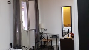 A bedroom with a bed, a desk, a chair, a mirror, and a TV. - Casa Provenza Rooms (Catania)