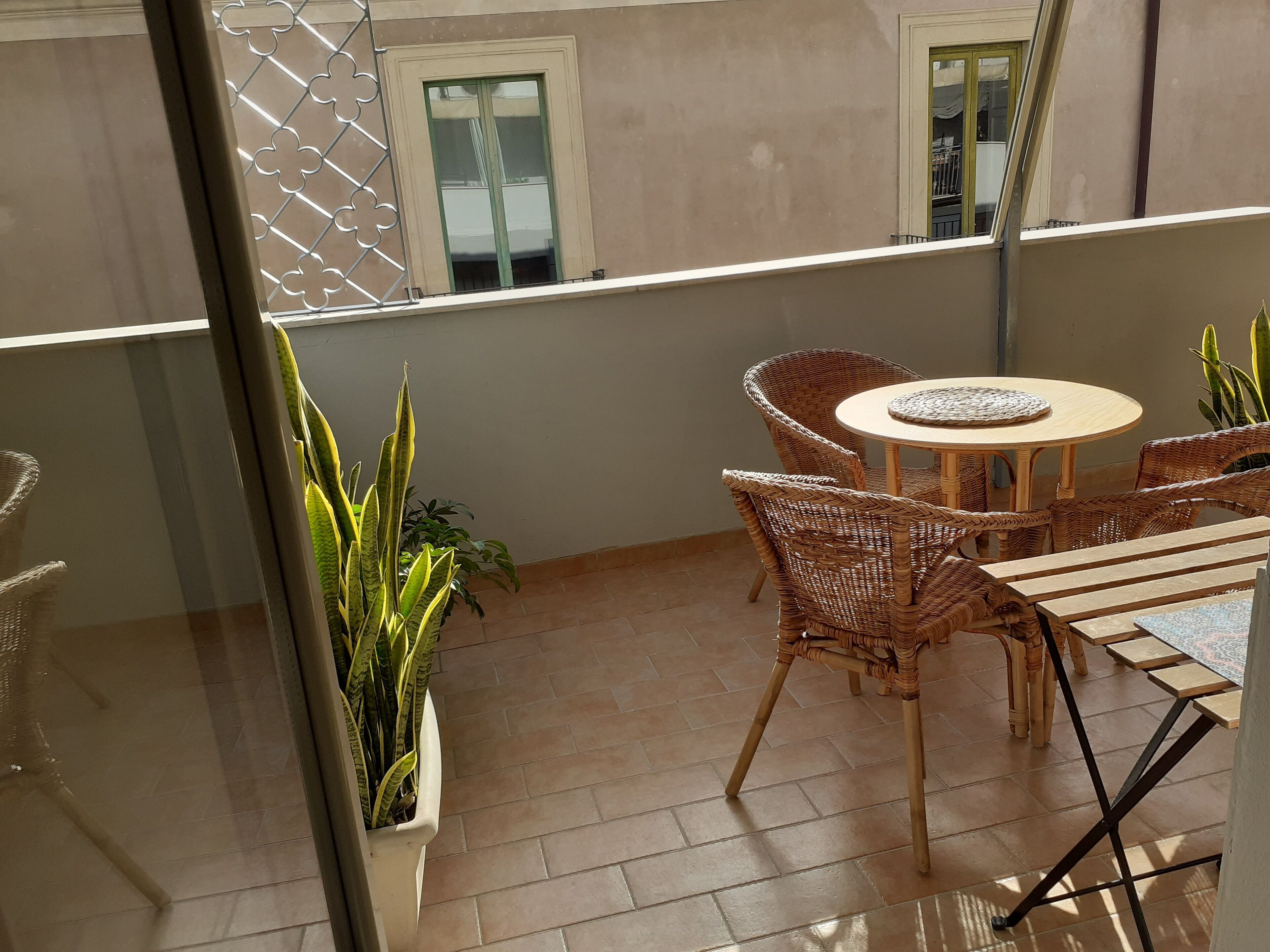 A balcony with wicker furniture, a round table, and potted plants.
