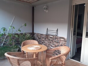 A balcony with wicker furniture, a small table, and potted plants. - Casa Provenza Rooms (Catania)