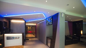 Eine moderne Hotelhalle mit einer Rezeption, einer Sitzecke und einem Flur zu den Zimmern.