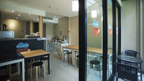 Ein Café mit Tischen und Stühlen, einer Theke mit einer Kaffeemaschine und einem Schild mit der Aufschrift 'CLOUD CAFE'.
