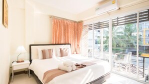 Quarto de hotel com cama, mesa de cabeceira, janela com persianas e vista para o exterior.