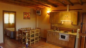 A cozy kitchen with wooden cabinets, a dining table with chairs, and a small TV.