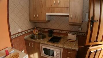 Una cocina compacta con muebles de madera, microondas, fregadero y tostadora.