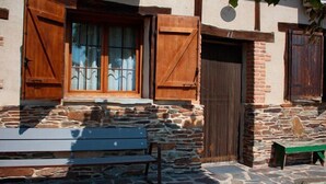 A stone building with wooden shutters and a bench.