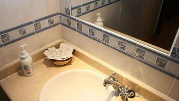 Un baño con lavamanos, espejo y artículos de aseo.