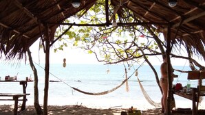 A beachside hut with a thatched roof, a table, and chairs. - The Sea At Lanta Hotel (Ko Lanta)