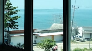 A view through a window with a view of the sea and a building with a red roof. - The Sea At Lanta Hotel (Ko Lanta)