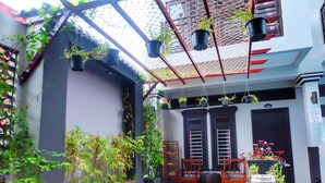 A covered outdoor area with a wooden bench, potted plants, and a small table with a bowl. - VIBOLA Guesthouse (Kampot)