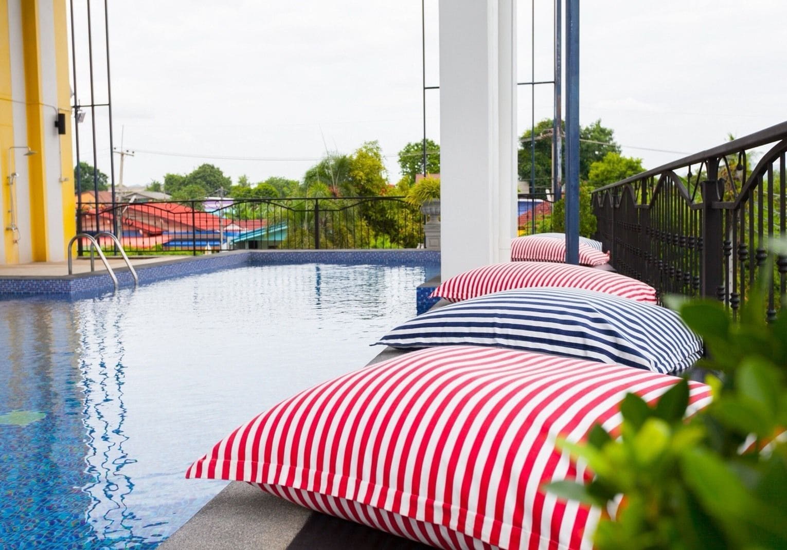 A swimming pool with a view of the surrounding area, including a fence and some greenery.