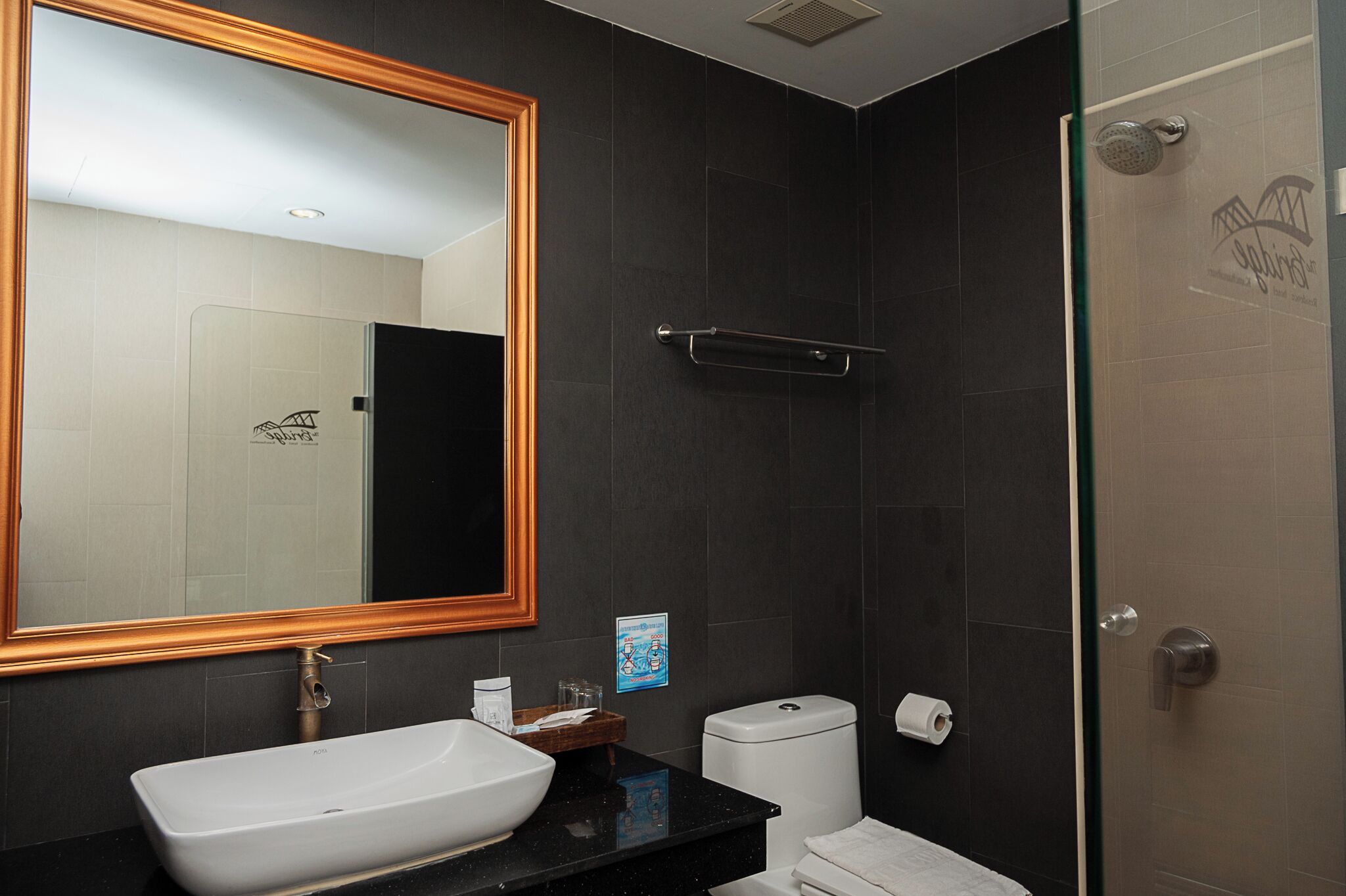 A modern bathroom with a large mirror, a white sink, a toilet, and a glass-enclosed shower.