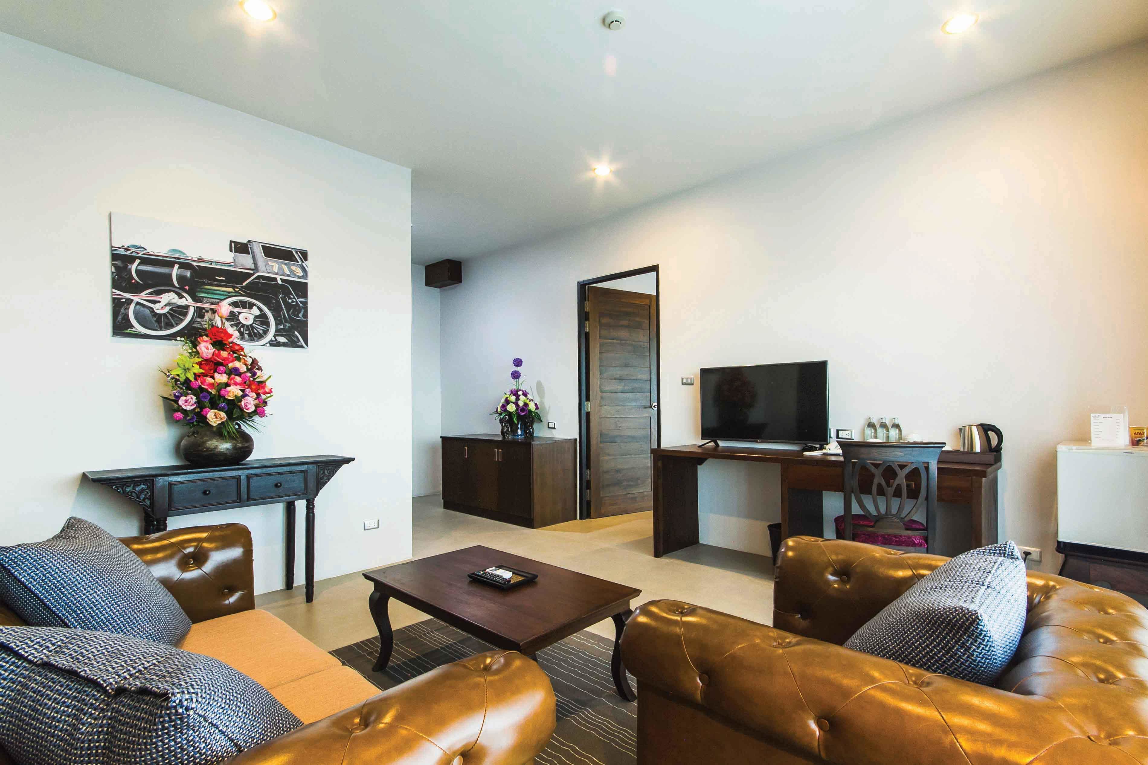A modern living room with leather sofas, a coffee table, a TV, and a desk with a computer.