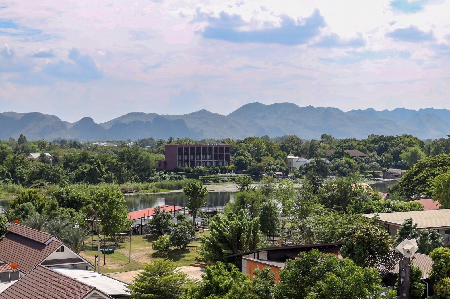 A view of a residential area with a large building, a lake, and mountains in the background.