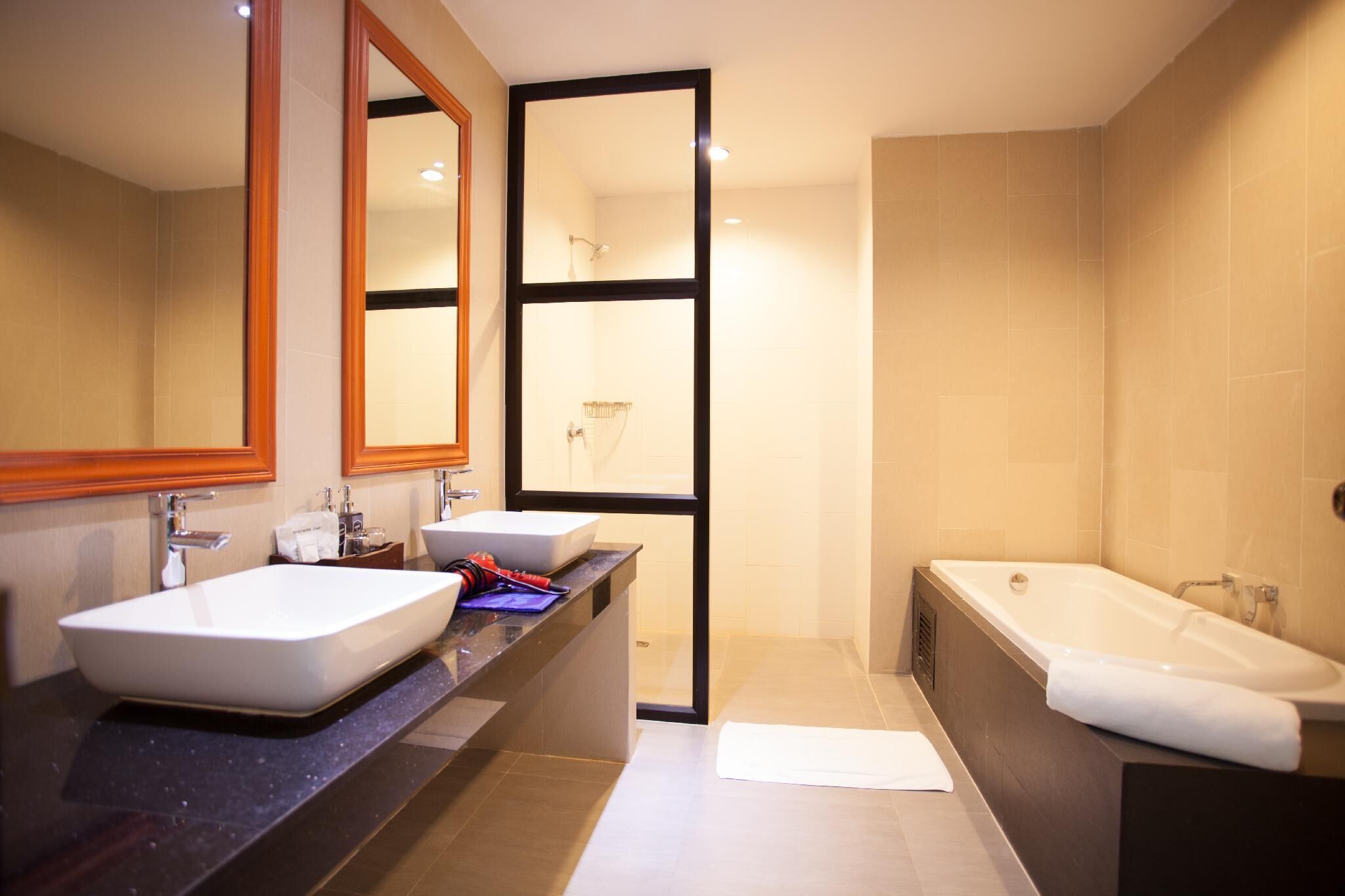 A modern bathroom with two sinks, a large mirror, and a bathtub.