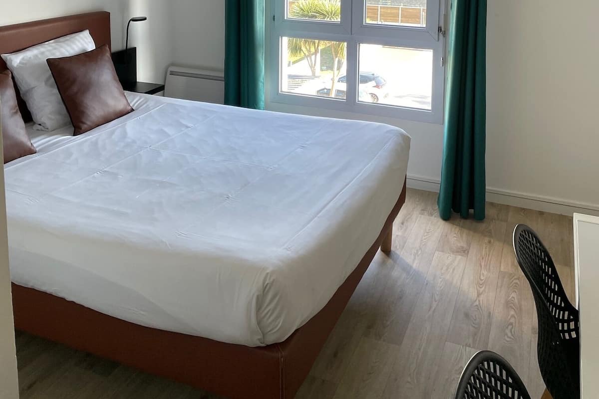 Une chambre d’hôtel avec un lit, une vue sur l’extérieur grâce à une porte coulissante et un tableau accroché au mur.
