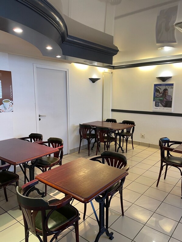 A dining area with multiple wooden tables and chairs, a white door, and wall-mounted lighting.
