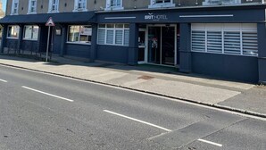 Een hotel met een opvallend 'HOTEL' bord, een 'BRIT HOTEL' bord en een 'BRIT' bord dat een nabijgelegen restaurant aangeeft.