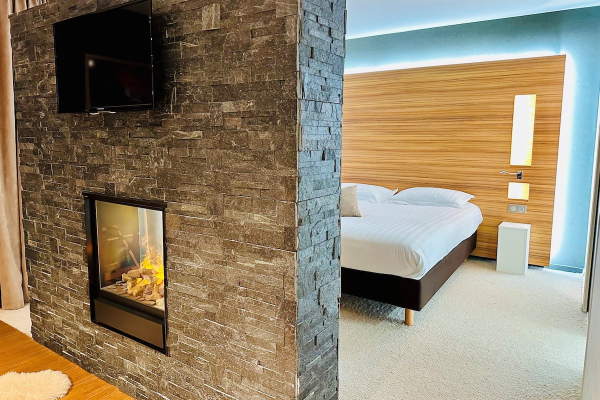 Ein Zimmer mit einer Steinwand, einem Kamin, einem Bett mit weißer Bettwäsche und einem Holzkopfende.