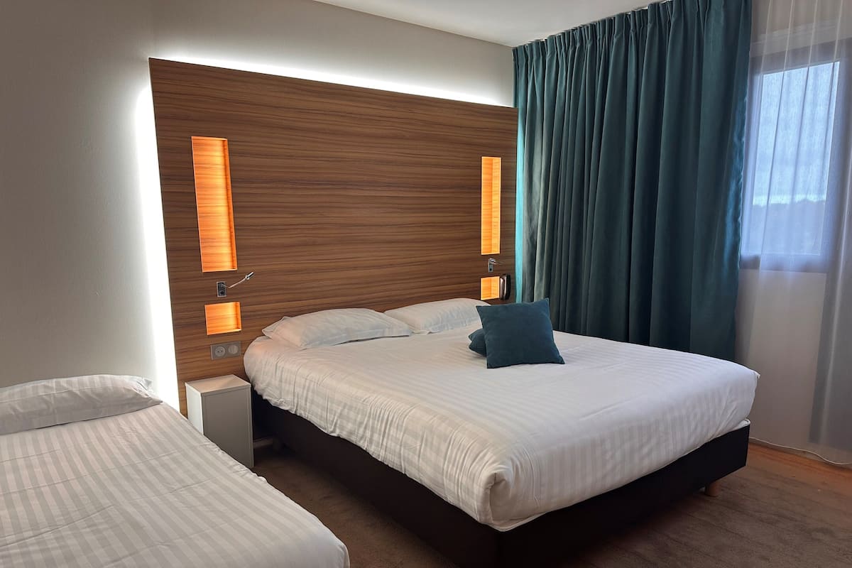 Ein modernes Hotelzimmer mit einem großen Bett, zwei Nachttischen und einem Holzkopfteil.