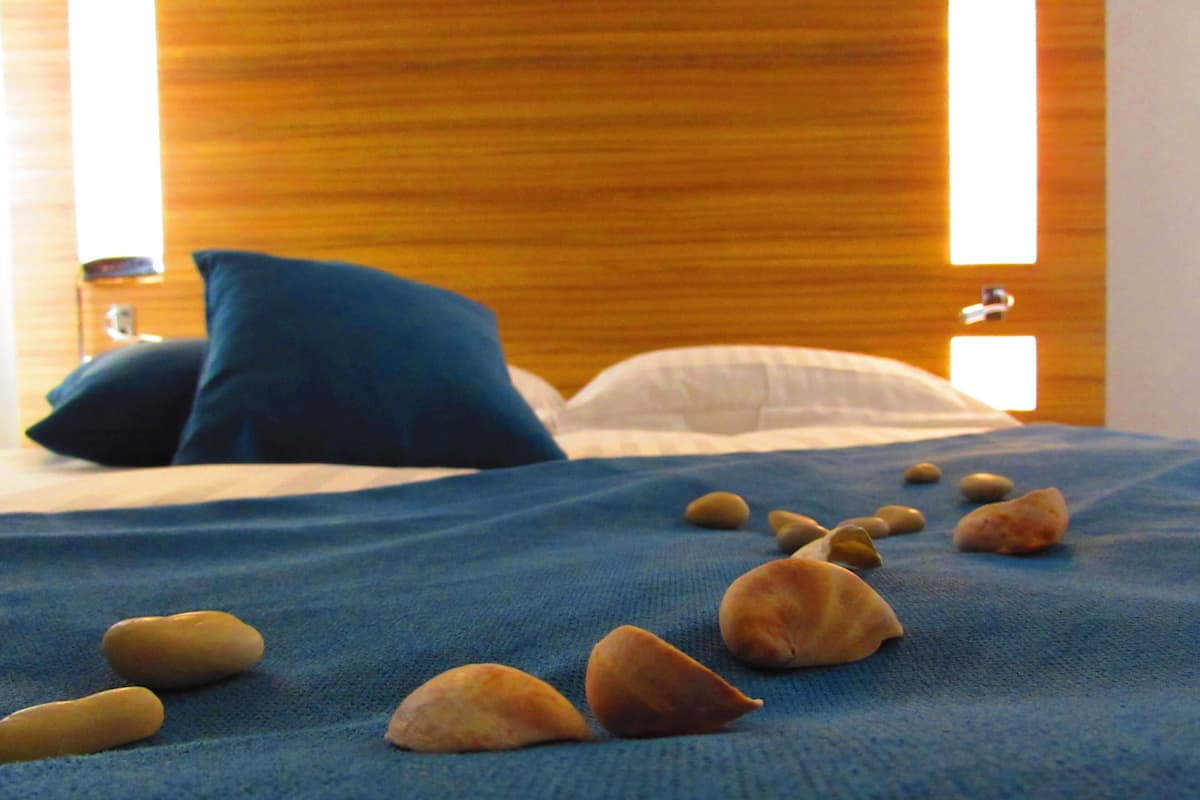 Ein Bett mit blauer Decke und ein paar Kieselsteinen darauf.