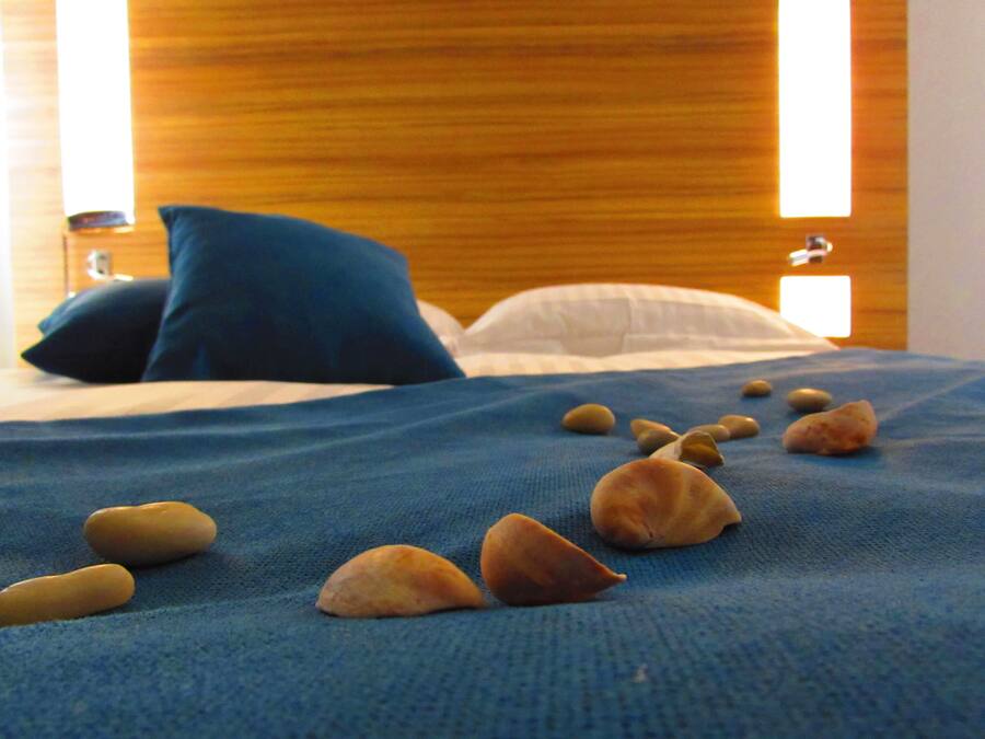 Una cama con un edredón azul y varias piedras encima.