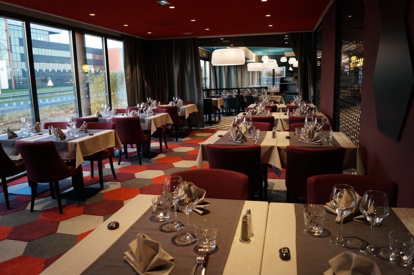 A restaurant with tables set for dining, large windows, and a view of the outside.