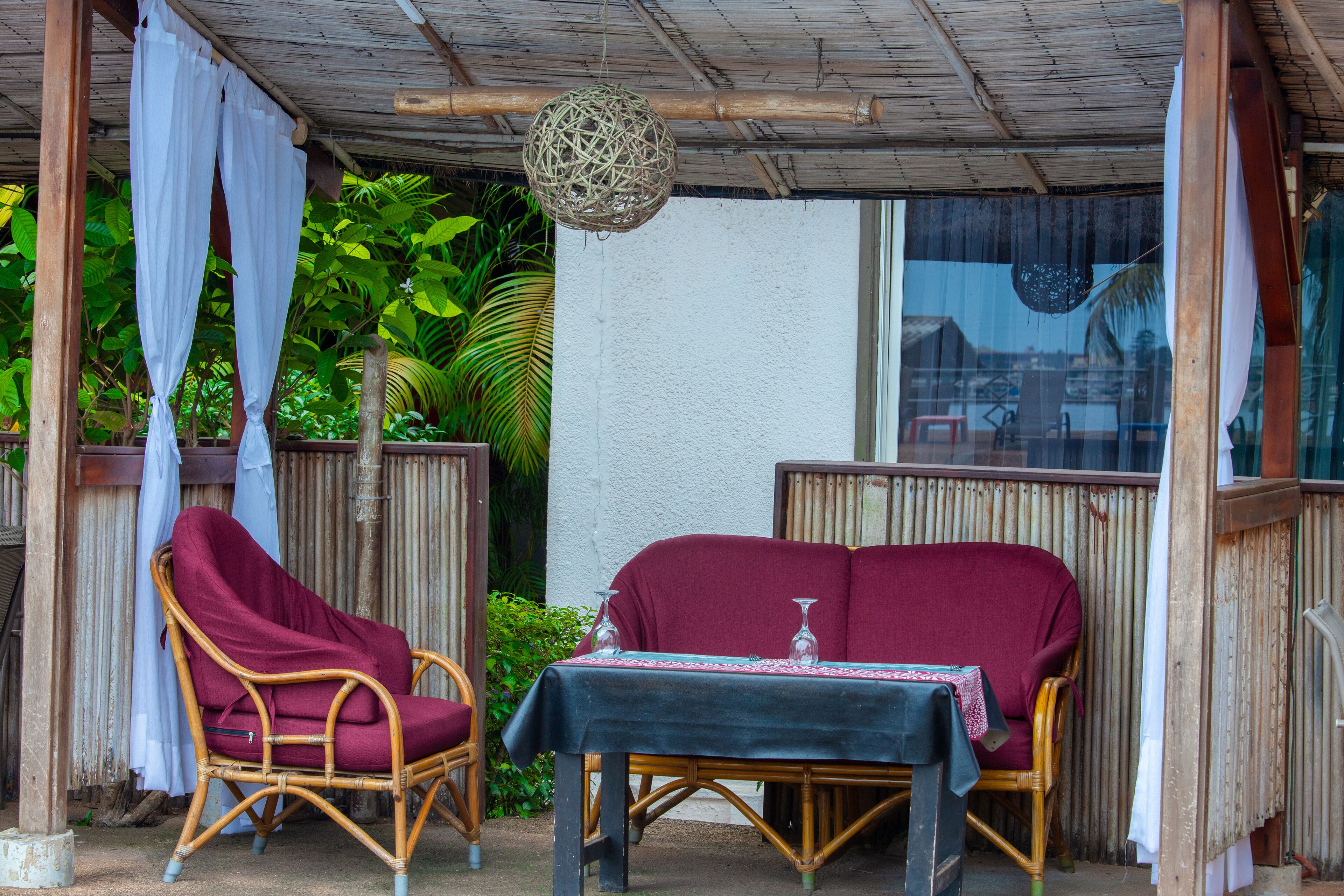 A covered outdoor seating area with wicker furniture and a table set for two.