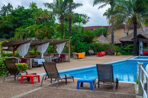 A poolside area with lounge chairs, a small pool, and a covered seating area with umbrellas.