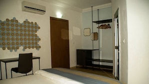 A bedroom with a bed, a desk, a chair, a wardrobe, and a mirror.