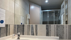 A modern bathroom with a large sink, a hand dryer, and a glass shower enclosure. - Brit Hotel Saint-Quentin (Fayet)