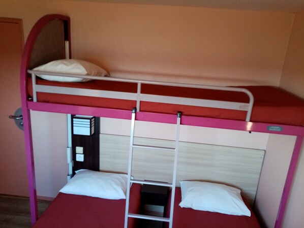 A bunk bed with a ladder, a single bed below, and a door to the left.