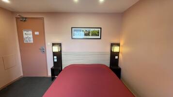 Een hotelkamer met een bed, een deur, een lijst met een afbeelding aan de muur en twee bedlampen.