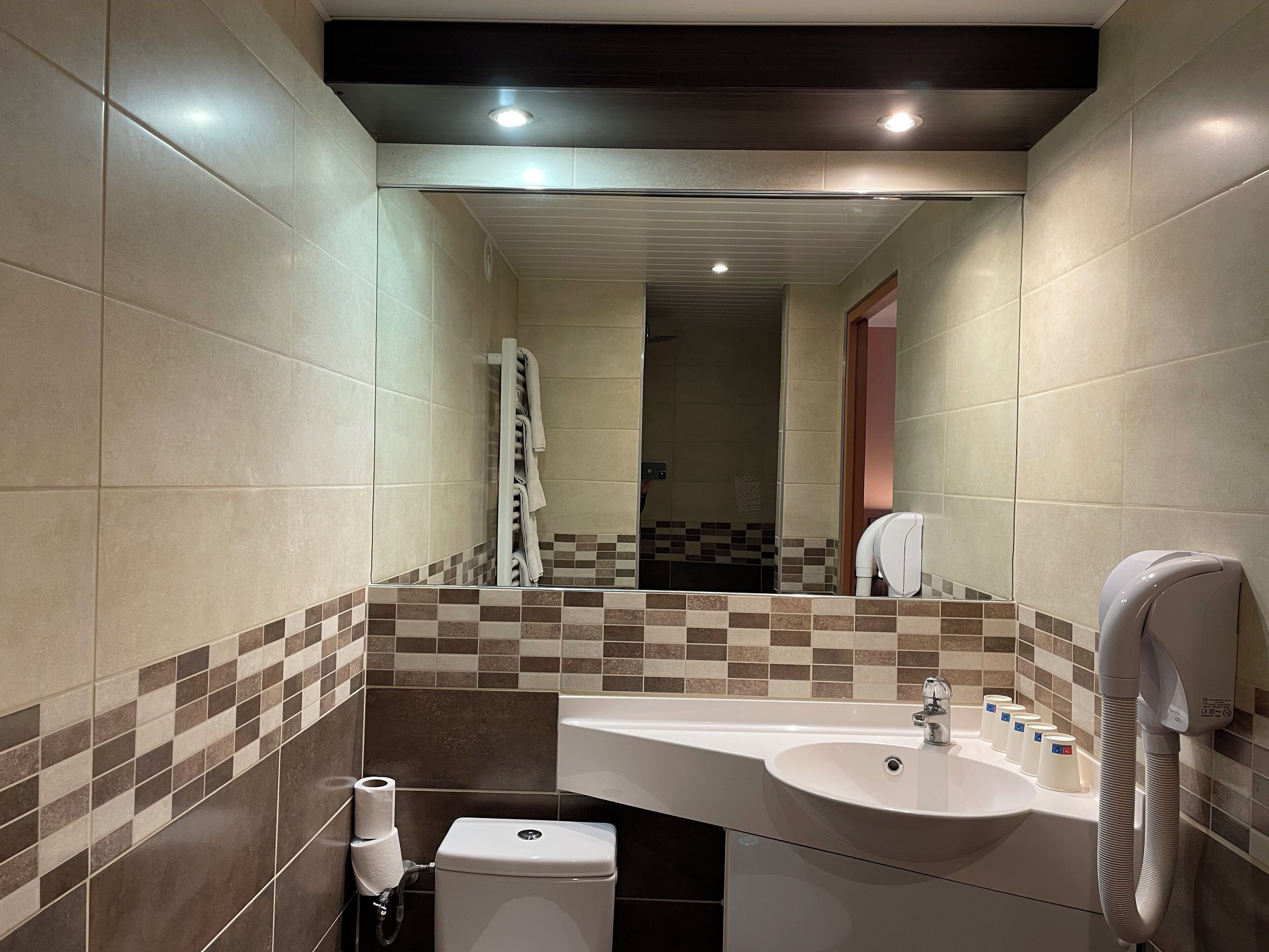 Een moderne badkamer met een grote wastafel, toilet en handdoekhouder.